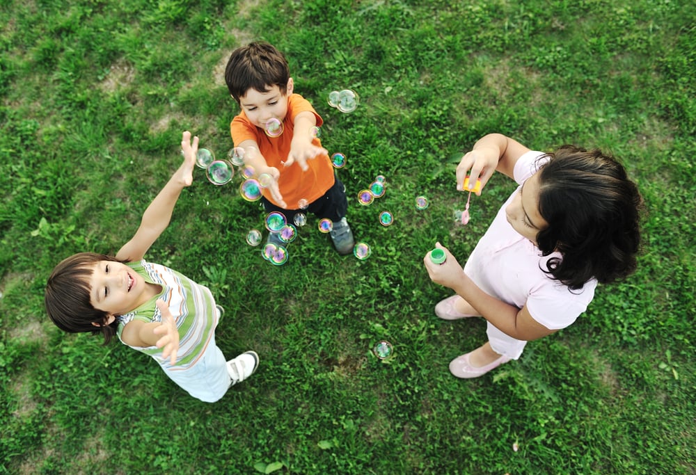 Small group of happy children making bubbles and playing together in nature
